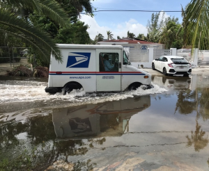 A mail truck drives through flooded streets in Miami.