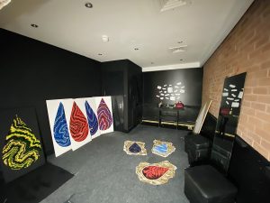 Interior view of the studio with painting leaning against the wall. All of the paintings seem to be of tear drop shaped images.